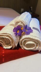 a towel with purple flowers on top of a bed at Pousada e Restaurante o Portuga in São Miguel dos Milagres