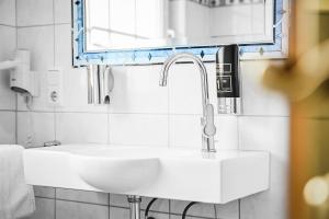 une salle de bain avec un lavabo blanc et un miroir dans l'établissement Landhaus Lenneper-Führt, à Kirchhundem
