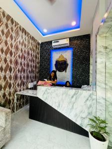 eine Frau, die an einem Tresen in einem Raum sitzt in der Unterkunft Hotel G7 in Indore