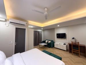 une chambre d'hôtel avec un lit, un canapé et une télévision dans l'établissement BedChambers Luxurious Aparthotel Near Medicity, à Gurgaon