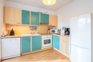 Una cocina con gabinetes azules y un refrigerador blanco. en Appartement 4 Pièces, 3 Chambres, en Les Sables-dʼOlonne 14 fotos más