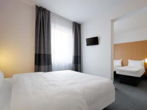 a bedroom with a large white bed and a window at B&B Hotel Prague City in Prague