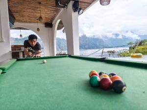 a man playing a game of pool on a pool table at Lushy Hostel Kintamani in Kubupenlokan