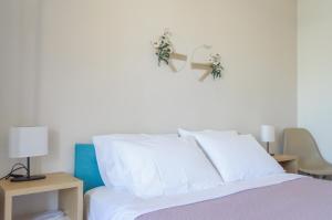 Una cama con almohadas blancas y plantas en la pared. en Ostria Rooms, en Palaiochóra
