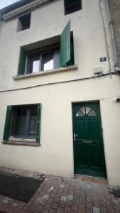 a building with a green door and two windows at Studio cosy dans le cœur de Castelsarrasin in Castelsarrasin