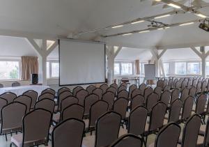 une salle vide avec une salle de conférence dotée de chaises et d'un écran dans l'établissement Hotel Marina Port, à Balatonkenese 88 autres photos