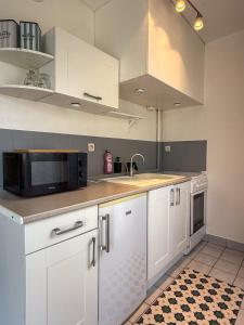 a kitchen with white cabinets and a microwave at Studio avec jardin et parking in Chartres