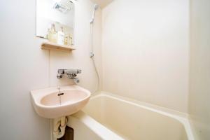 łazienka z umywalką i wanną w obiekcie Guest House NANMO w mieście Minami-jūichijō