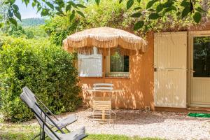a patio with a table and chairs and an umbrella at Le Mas Du Loup in Moustiers-Sainte-Marie