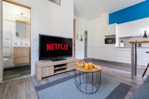 Una sala de estar con un televisor y una mesa. en Le Coq Albert II - Monaco border - WiFi, en Beausoleil