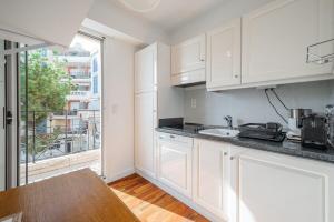 a kitchen with white cabinets and a large window at Le COQ Bleu d'Azur - Piscine - Parking! in Menton