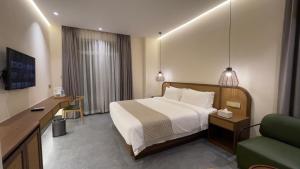 Un dormitorio con una cama, un escritorio y un sofá. en Joya Hotel, en Phnom Penh