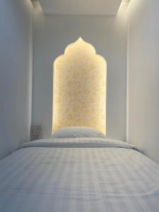 a white bedroom with a bed with a white headboard at One life Hostel in Chiang Mai