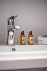 three bottles of soap sitting on a bathroom sink at Le COQ Symphonie - Parking - AC - WIFI in Menton