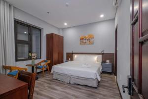 a bedroom with a bed and a table and a desk at Silana River Light Hotel in Da Nang