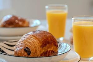 une table avec une assiette de pâtisserie et deux verres de jus d'orange dans l'établissement Le Coq Casamare - Air conditioning - WiFi - New - Sea, à Menton