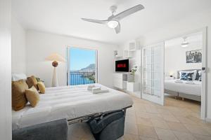 a white bedroom with a large bed and a living room at Le COQ Gabriel - Parking - Amazing view in Roquebrune-Cap-Martin