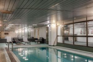 a swimming pool in a building with chairs and tables at Scandic Mikkeli in Mikkeli