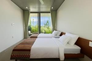 two beds in a room with a window at Marvelous Homestay Hoi An in Dien Ban