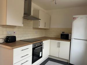 a kitchen with white cabinets and a white refrigerator at 4 bedroom house in Shotton Colliery in Durham