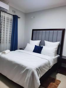 a bedroom with a large white bed with a blue curtain at Kwilanzi Apartments in Lusaka