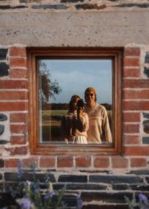 een groep mensen weerspiegeld in een raam bij Stylish Dairy Cottage by the Sea- Romantic Luxury in Port Elliot