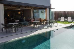 a patio with tables and chairs next to a swimming pool at Sevilla Green Suites in Alcalá de Guadaira