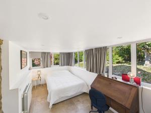 a bedroom with a bed and a desk and windows at Superbe chaumière pour 6 personnes avec jardin in Ploeren