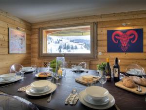 a dining room with a table with food and wine glasses at Chalet Le Mousqueton - OVO Network in La Clusaz