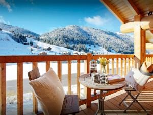 a porch with a table and chairs and a snowy mountain at Chalet Le Mousqueton - OVO Network in La Clusaz +27 photos