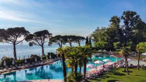 a pool with chairs and umbrellas next to the ocean at Hotel Corte Valier in Lazise