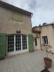 a house with green and white doors and a courtyard at Gîte Léonfine in Le Cannet-des-Maures +3 photos