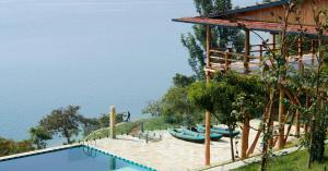 a swimming pool next to a building with boats on it at Umutuzo Lodge Kivu Lake in Buhoro +123 photos