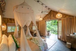 a bedroom with a bed with mosquito netting at Pramana Giri Kusuma in Payangan