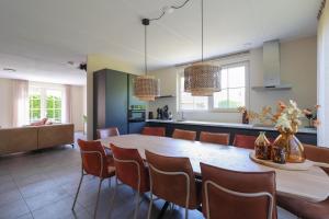 uma cozinha e sala de jantar com mesa e cadeiras em Beachvilla Royaal met Wellness bubbelbad & Sauna - 10 personen em Holle Poarte