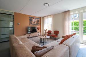 uma sala de estar com um sofá e uma TV em Beachvilla Royaal met Wellness bubbelbad & Sauna - 10 personen em Holle Poarte