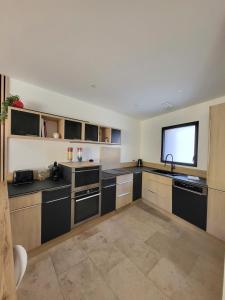 a large kitchen with black counters and a window at Maison de charme avec Piscine-Clim-Plage à 10min in Fleury +39 photos