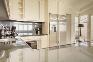 a kitchen with white cabinets and a stainless steel refrigerator at Dijkvilla - 5 personen in Holle Poarte