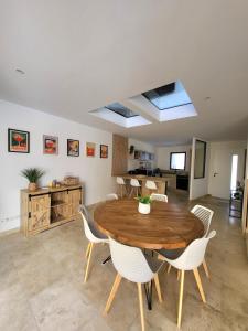 a dining room with a wooden table and white chairs at Maison de charme avec Piscine-Clim-Plage à 10min in Fleury
