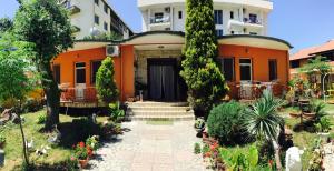 una casa arancione con scale e piante in un cortile di Guroal Holiday House a Shëngjin