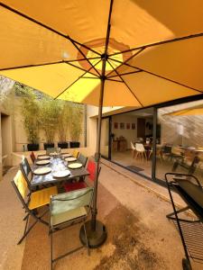 a patio with a table with a yellow umbrella at Maison de charme avec Piscine-Clim-Plage à 10min in Fleury