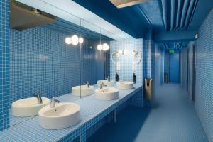 a blue tiled bathroom with four sinks and mirrors at Latroupe Poblenou Beach in Barcelona