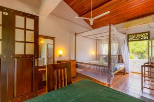 a bedroom with a canopy bed and a desk at Serendipity Beach Hotel in Unawatuna