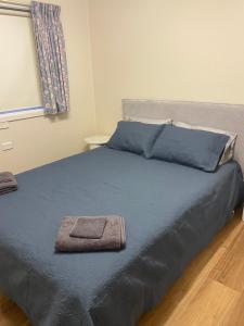 a bed with blue sheets and a towel on it at 3 bedroom Creswell Street Cottage - Pet Friendly in West Wyalong