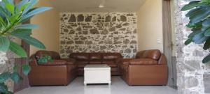 a living room with two leather couches and a stone wall at Virat Resorts, Sariska Rajasthan in Bairāt