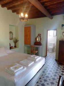 a bedroom with a large white bed and a bathroom at MYRTIA , Traditional Kimolos house in Kimolos