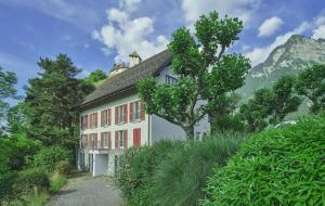 a building with a tree in front of a mountain at Gästehaus Gutenberg - Self-Check-in in Balzers