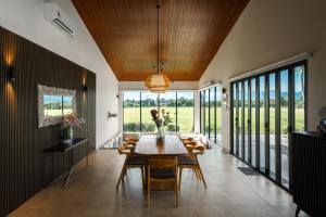 Un comedor con mesa y sillas en Villa Moo Moo, Pool Villa with Sunset & Paddy Field Views, en Langkawi Intl