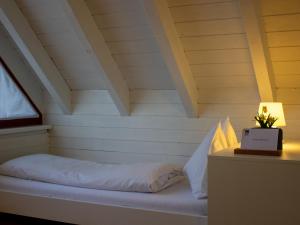 a bed in a room with a white wall at Gästehaus Gutenberg - Self-Check-in in Balzers