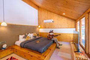 Zostel Kasol, Main Market في كاسول: امرأة تجلس على سرير وتعزف على الغيتار